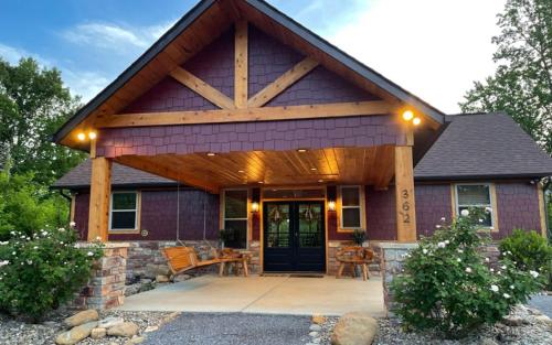a house with a gambrel roof with a patio at Holly Ridge Hideaway in Gatlinburg