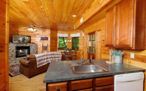 a kitchen with a sink and a living room with a fireplace at Smoky Getaway in Gatlinburg