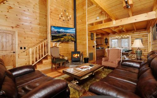 a living room with leather furniture in a log cabin at New Fox Lodge in Gatlinburg