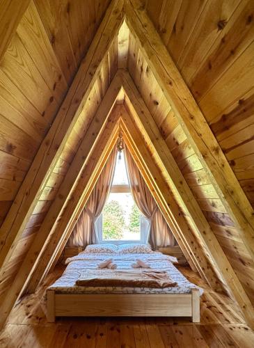 a bed in the attic with a window at Bungalovi Glava Bukovice in Žabljak