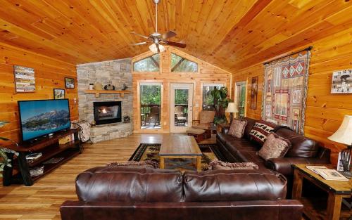 a living room with a leather couch and a fireplace at Dogwood Acres in Pigeon Forge