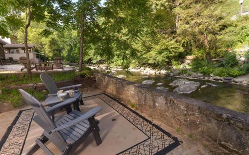two chairs sitting on a patio next to a stream at On River Time in Gatlinburg