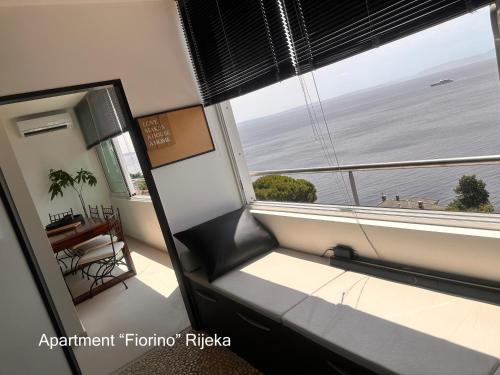 a window seat in a room with a view of the ocean at Rijeka Fiorino Apartment in Rijeka
