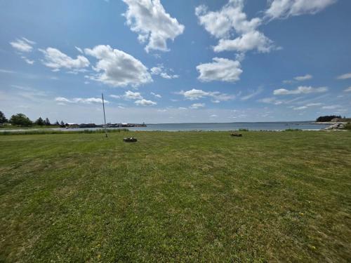 a field of grass with the ocean in the background at Hunts Point 1-BR Coastal Retreat - Cottage # 7 in Summerville Centre