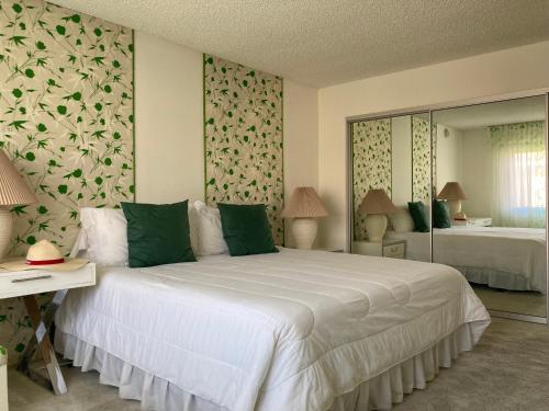 a bedroom with a large white bed with green pillows at Relaxing Rancho Mirage home inside Sunrise Country Club in Rancho Mirage
