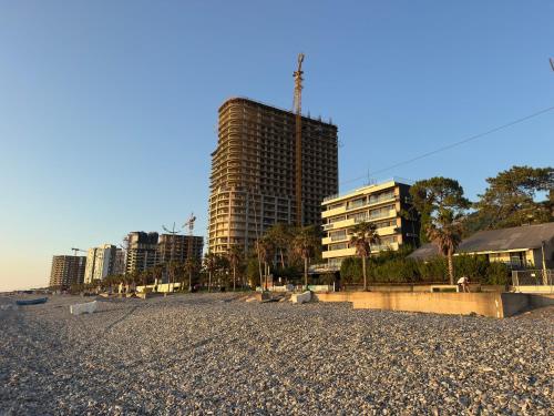 a building on the beach with buildings in the background at Gonio Studio in Batumi in Kvariati