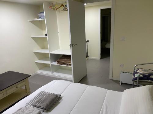 a white bedroom with a bed and a desk and shelves at Pontevedra Centro adosado in Pontevedra