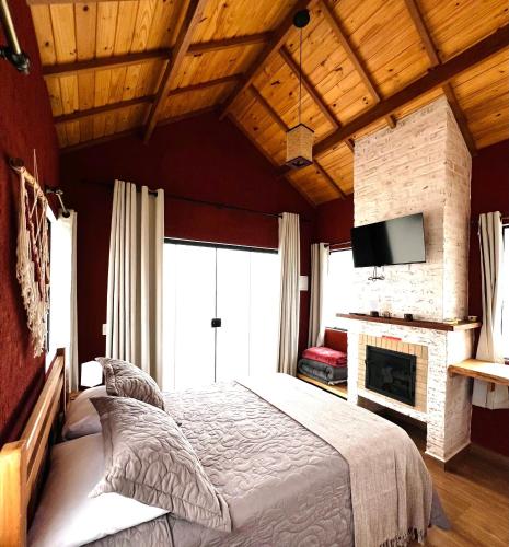 蒙特韦尔迪Vila Ninho da Maritaca的带一张大床和一个壁炉的卧室