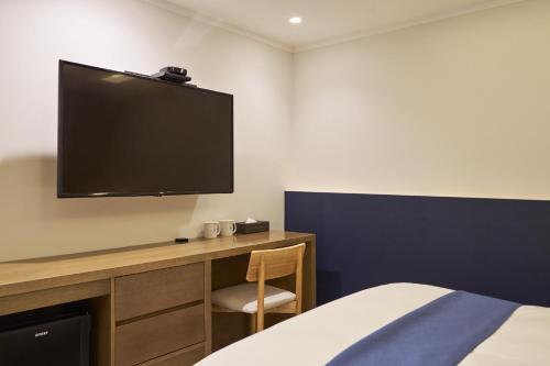 a bedroom with a desk with a tv on the wall at Blueduck hotel in Seoul