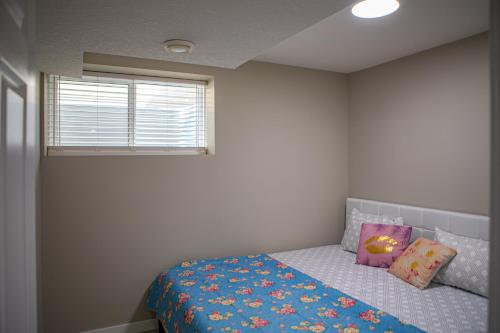 カルガリーにあるModern 2-Bedroom Suite with Private Access - 10 minutes from Calgary Airportの青い毛布と窓のあるベッドのある寝室