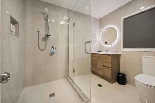 a bathroom with a shower and a toilet and a television at Aroha Motel & Apartments in Auckland