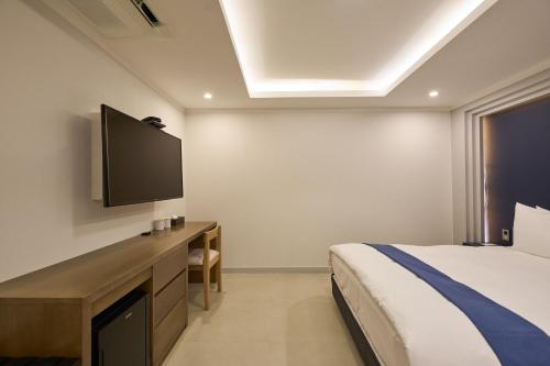 a bedroom with a bed and a flat screen tv at Blueduck hotel in Seoul