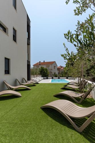 a row of chaise lounge chairs on a lawn next to a building at Villa SHARK 2 with a pool in Novalja