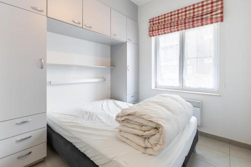 a bedroom with a bed with white walls and a window at Plaza 305-Gv03 in Sint-Idesbald