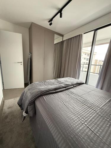 a bedroom with a bed and a large window at Stay Santos - Moderno e Bem Localizado in Santos