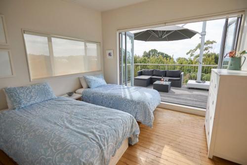 Waiheke IslandにあるBeachlovers Onetangi - Stay Waihekeのベッドルーム1室(ベッド1台付)、パティオ(パラソル付)
