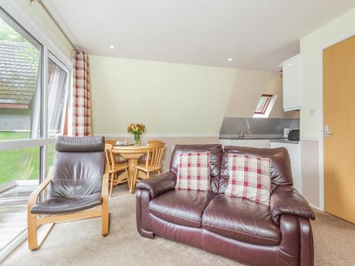 Una sala de estar con un sofá de cuero y una mesa. en Gorse Lodge - Uk7050, en Glenurguhart