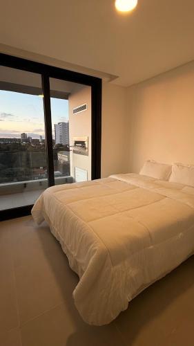 una camera da letto con un letto grande e una grande finestra di Edificio vivo costanera a Encarnación