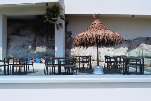 a group of tables and chairs with a straw umbrella at Antico Borgo dei Templi in Agrigento