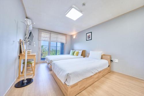Un dormitorio con dos camas y una ventana. en Jeju Happiness Pension, en Jeju