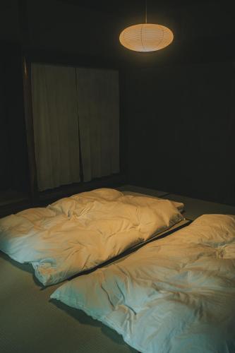 an unmade bed in a dark room with a light at ame nakasendo - A 150 years old private kominka along the Nakasendo trail - in Nagiso