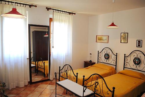 a bedroom with two beds and a mirror at Le Corolle in Montepulciano