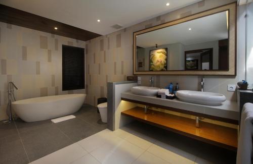 a bathroom with two sinks and a tub and a mirror at Sagara Villas and Suites Sanur by AHM in Sanur