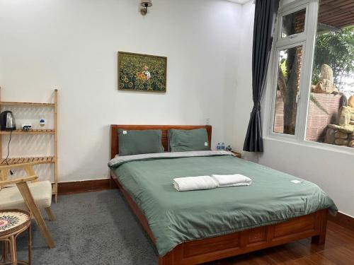 a bedroom with a bed with green sheets and a window at 3 Tầng Mây Homestay & Coffee in Da Lat