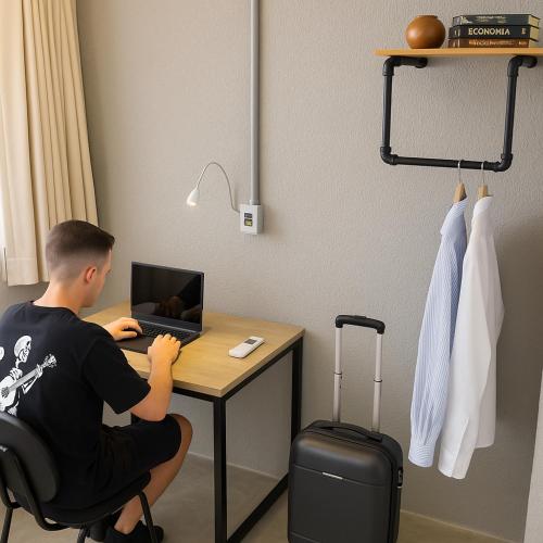 a man sitting at a desk with a laptop computer at Joy Hostel & Suítes in Brasilia