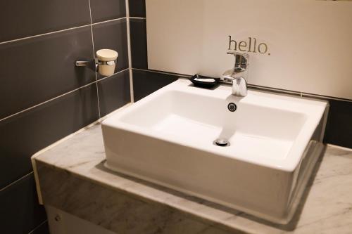 a white sink in a bathroom with a hello sign on the wall at 호텔 인썸니아 Hotel Insomnia 失眠酒店 in Daegu