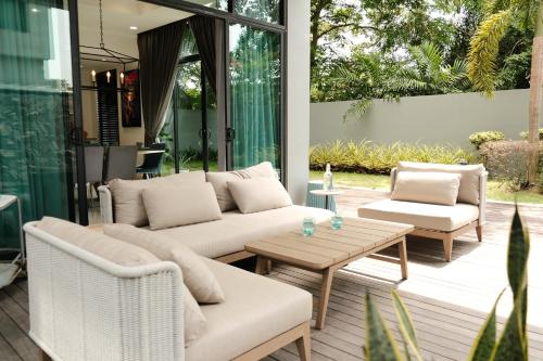a patio with couches and a table and chairs at La Villa Langkawi - Private Pool in Pantai Cenang
