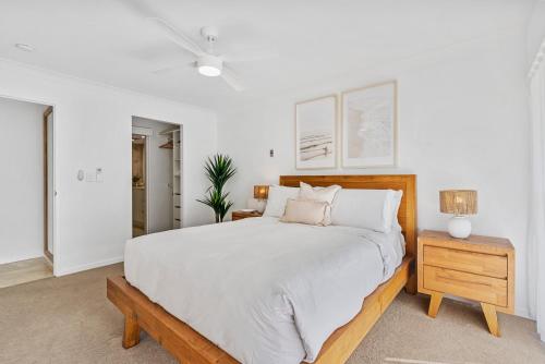 a white bedroom with a large bed and a table at Sun-Kissed Escape - Broadbeach Gem - Hosted by Coastal Letting Co. in Gold Coast