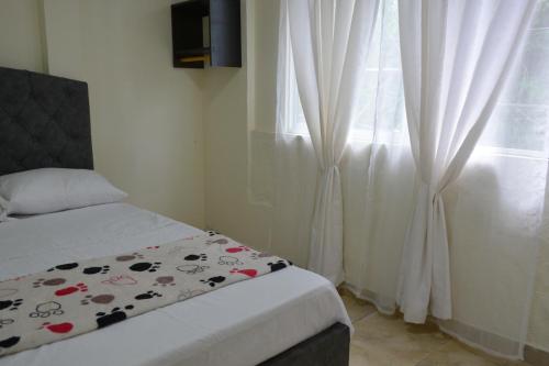 a bedroom with a bed and a window with curtains at Casa Hotel Descanso Quindiano in Montenegro