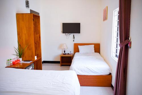 a bedroom with two beds and a tv on the wall at Gold Stone Hoi An Homestay in Hoi An