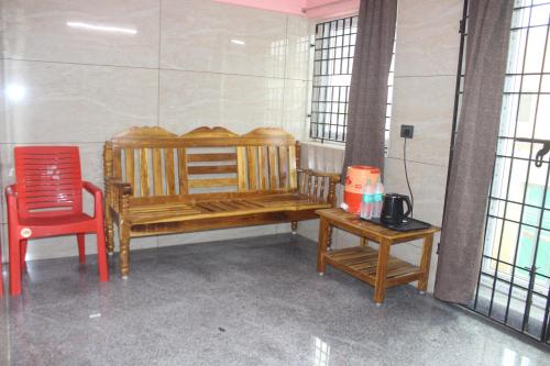 a room with a wooden bench and a red chair at Shaan stay inn in Kanchipuram