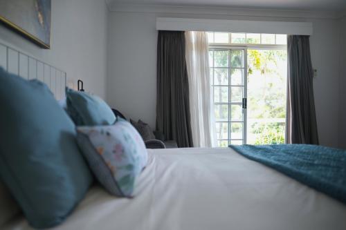a bedroom with a bed with blue pillows and a window at The Clan Terrigal in Terrigal