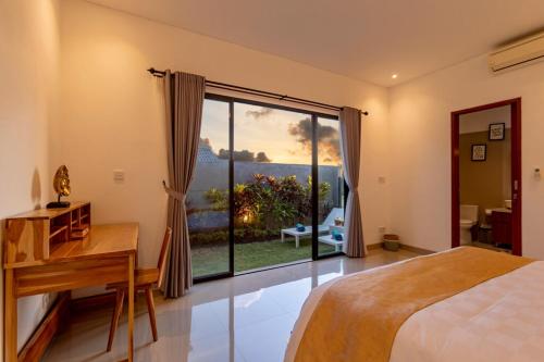 a bedroom with a bed and a desk and a window at Villa Uma Tegal Cemagi in Cemagi