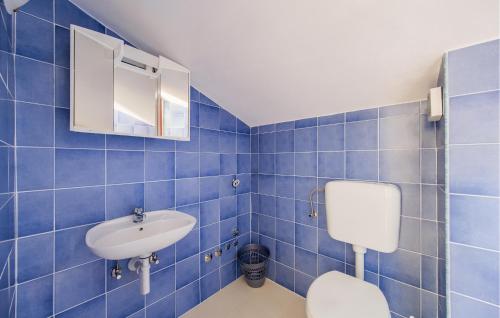 a blue tiled bathroom with a toilet and a sink at 1 Bedroom Awesome Home In Bale in Krmed