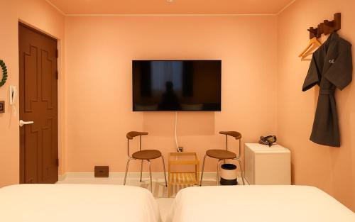 a bedroom with a bed and a tv on the wall at Gangneung Harubam in Gangneung