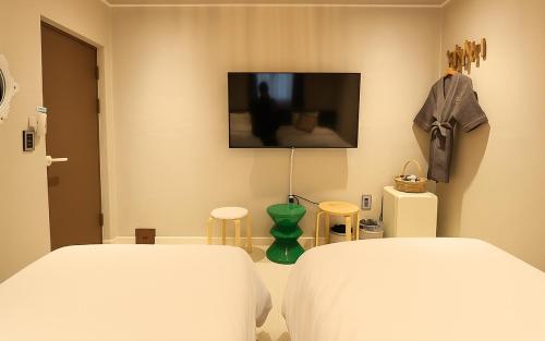 a bedroom with a bed and a tv on the wall at Gangneung Harubam in Gangneung