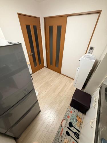 an empty room with a kitchen with a refrigerator and a door at 華宝民泊 in Wada