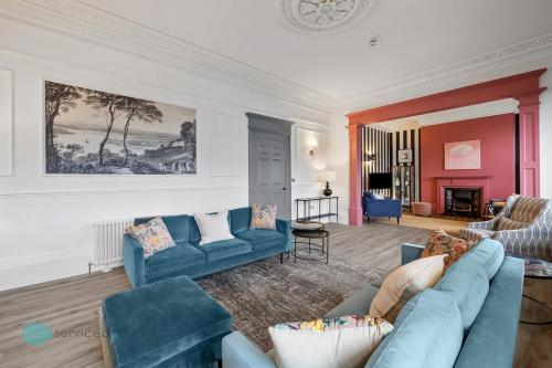 a living room with blue couches and a fireplace at Huge spacious 8 bed luxury villa in Plymouth