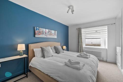 a blue bedroom with a bed with two towels on it at 2 Bed - Apartment No. 1 Windsor Villas in Plymouth