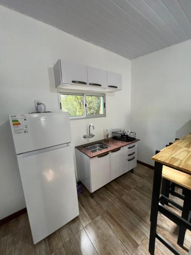 una cucina con un frigorifero bianco e un tavolo di Cabaña a Estrenar en Santa Ana a Santa Ana