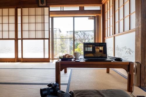a laptop sitting on a table in a room with windows at 古民家一棟貸別荘 しずく亭 -Kominka SHIZUKU tei- in Mobara