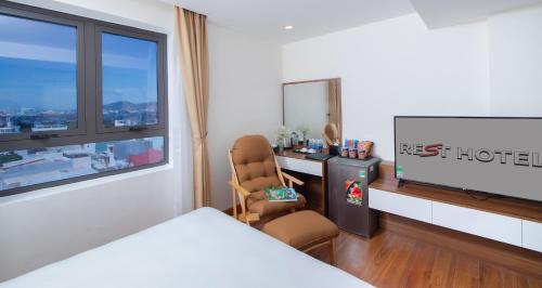 a bedroom with a television and a desk with a chair at Rest Hotel & Apartment in Da Nang