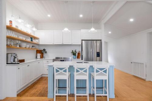 a kitchen with white cabinets and a blue island with stools at Sea Sage Cottage 4703 in Yeppoon