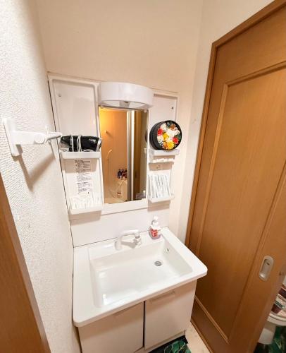 a bathroom with a white sink and a mirror at 華宝民泊 in Wada