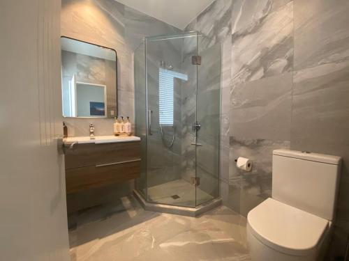 a bathroom with a shower and a toilet and a sink at Your Modern Private Room Awaits in Westgate in Auckland