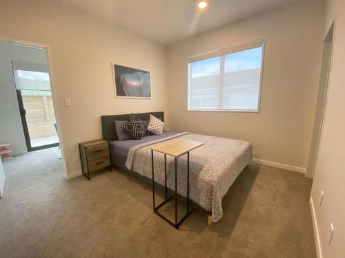 a bedroom with a bed with a table in it at Your Modern Private Room Awaits in Westgate in Auckland